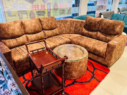 Brown corner sectional sofa with a glass-top coffee table and wooden side table, displayed on a red rug on the showroom floor